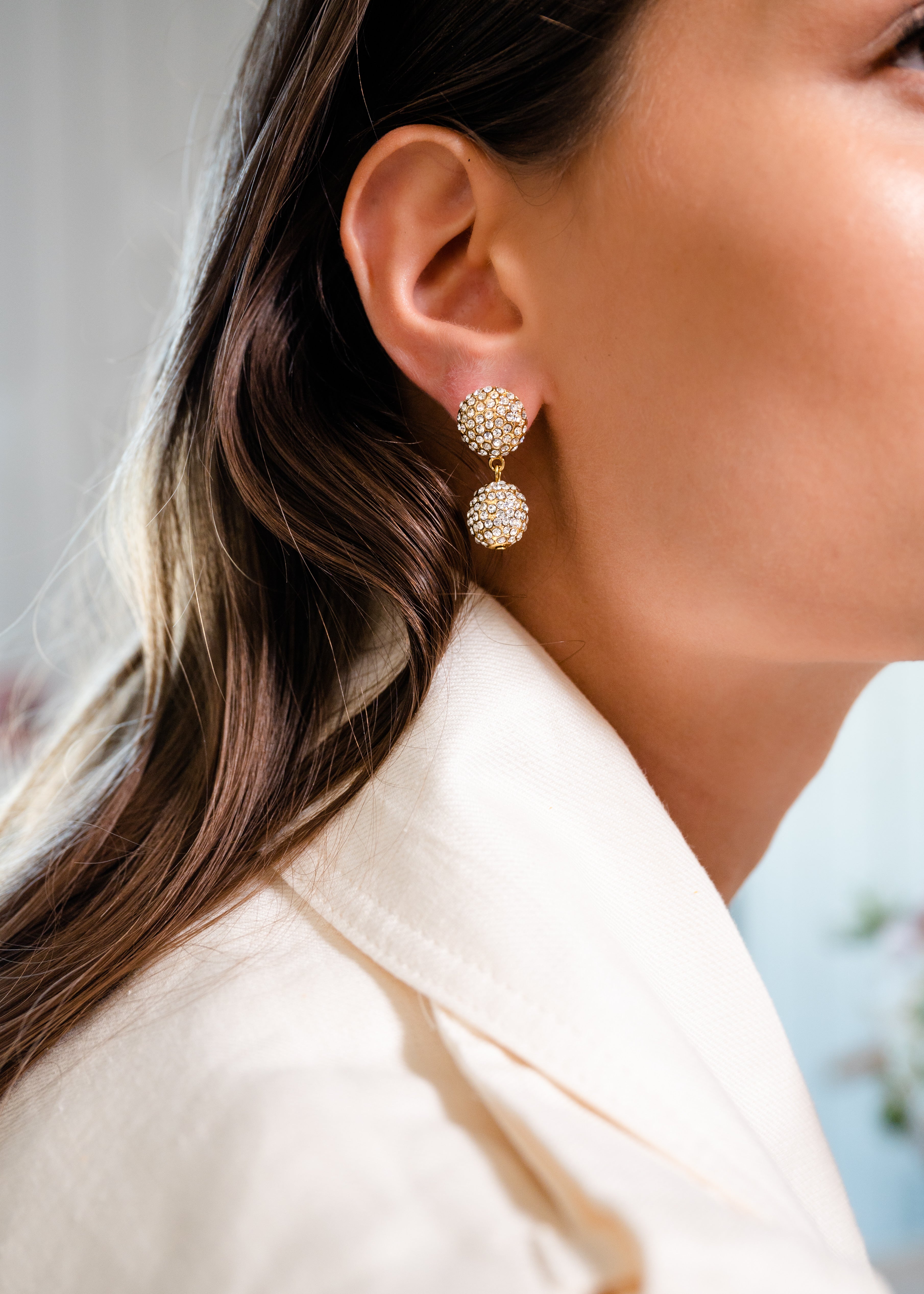 Model in white wearing Pave Ball 2 Drop earrings