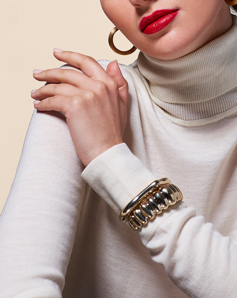 Model in white wearing Ribbed Hoop Earring and Heritage Bracelet