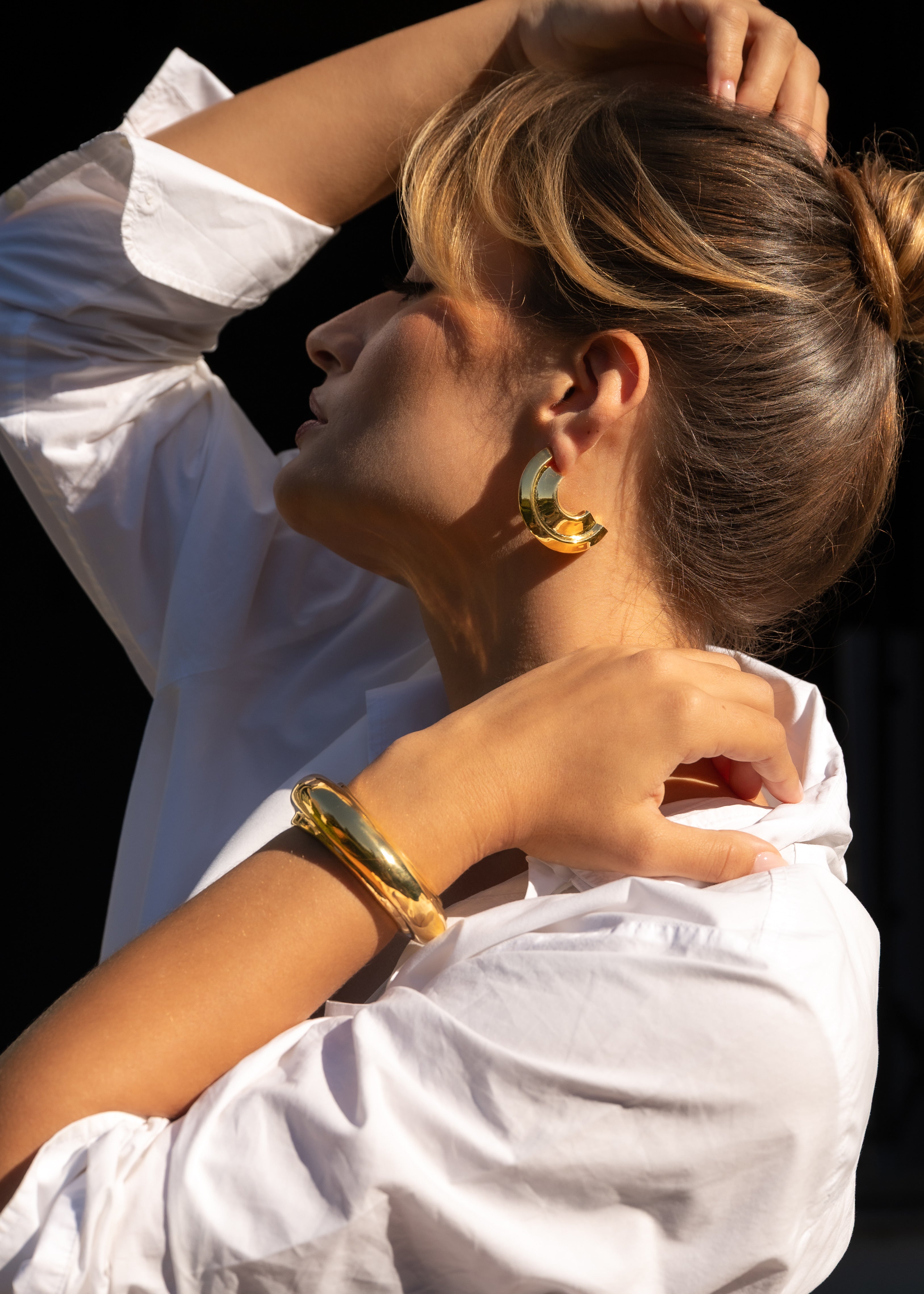 Person wearing gold earrings and bracelet