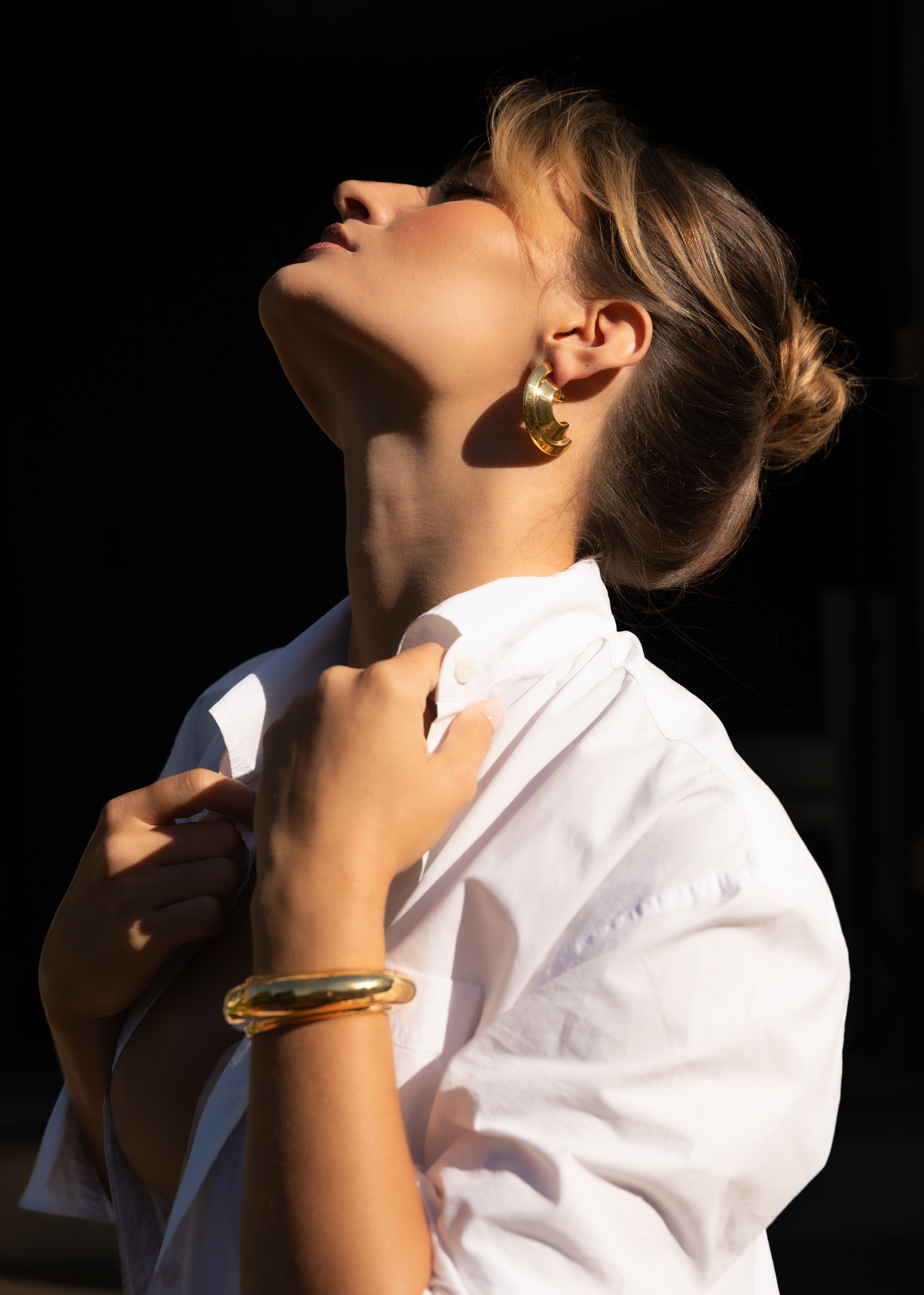 Woman wearing a white shirt with gold jewelry